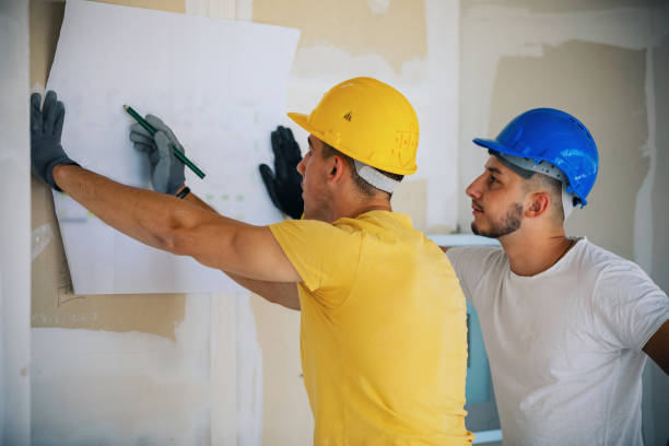 Construction workers cooperating while analyzing housing project in apartment.